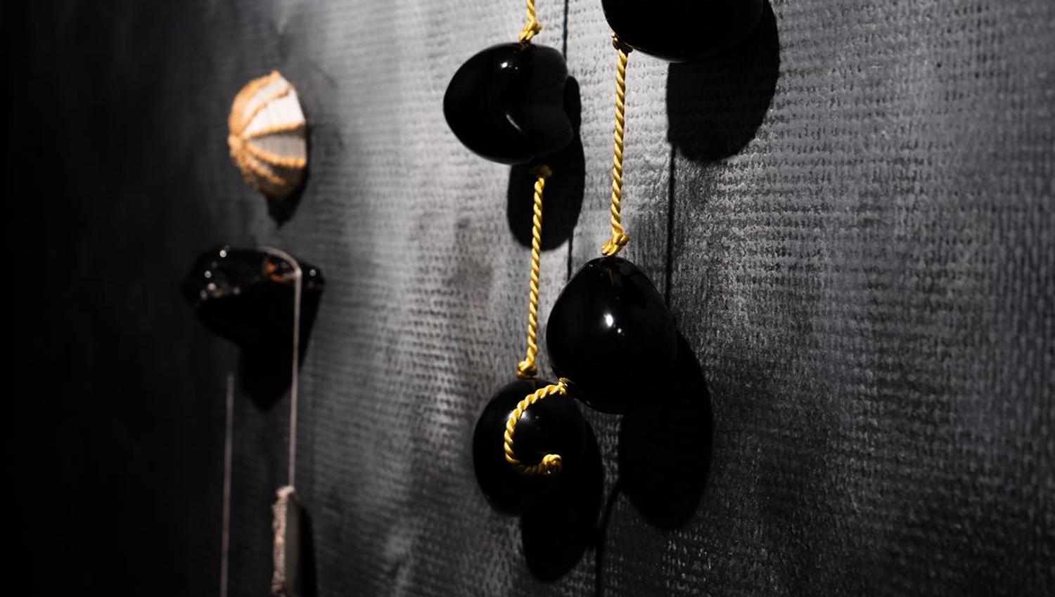 Dark wall installation with hanging glossy organic shapes.