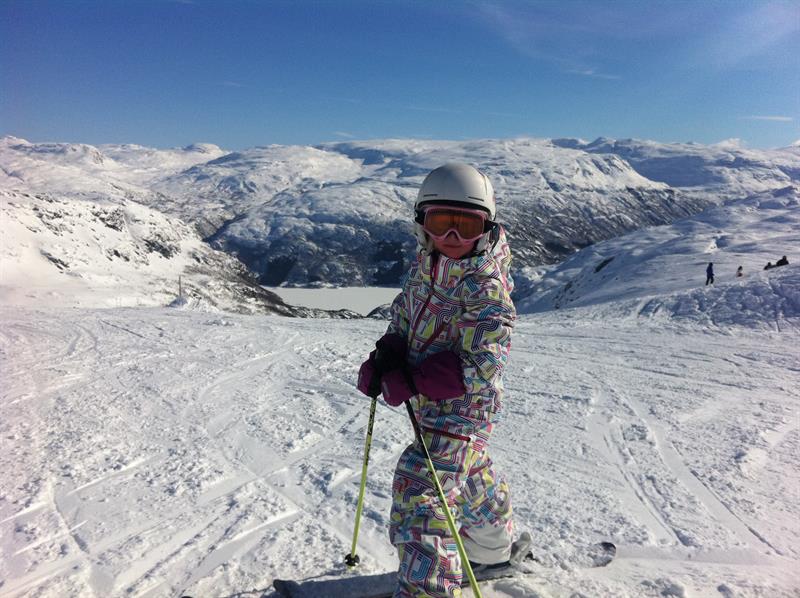 Kind auf Skiern im Røldal Skigebiet mit herrlichem Blick auf Berge und Fjord.
