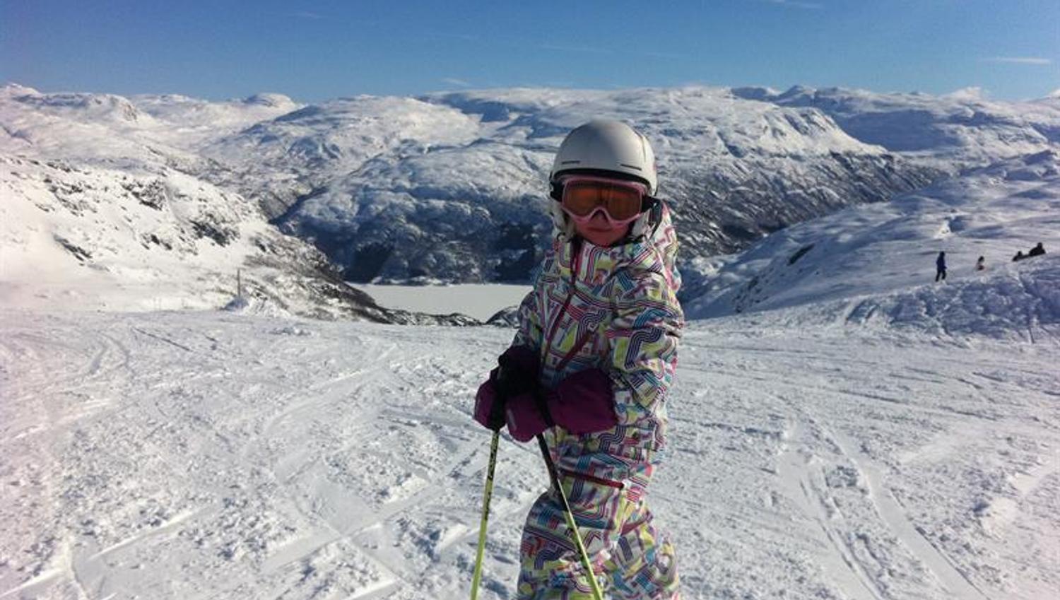 Kind auf Skiern im Røldal Skigebiet mit herrlichem Blick auf Berge und Fjord.