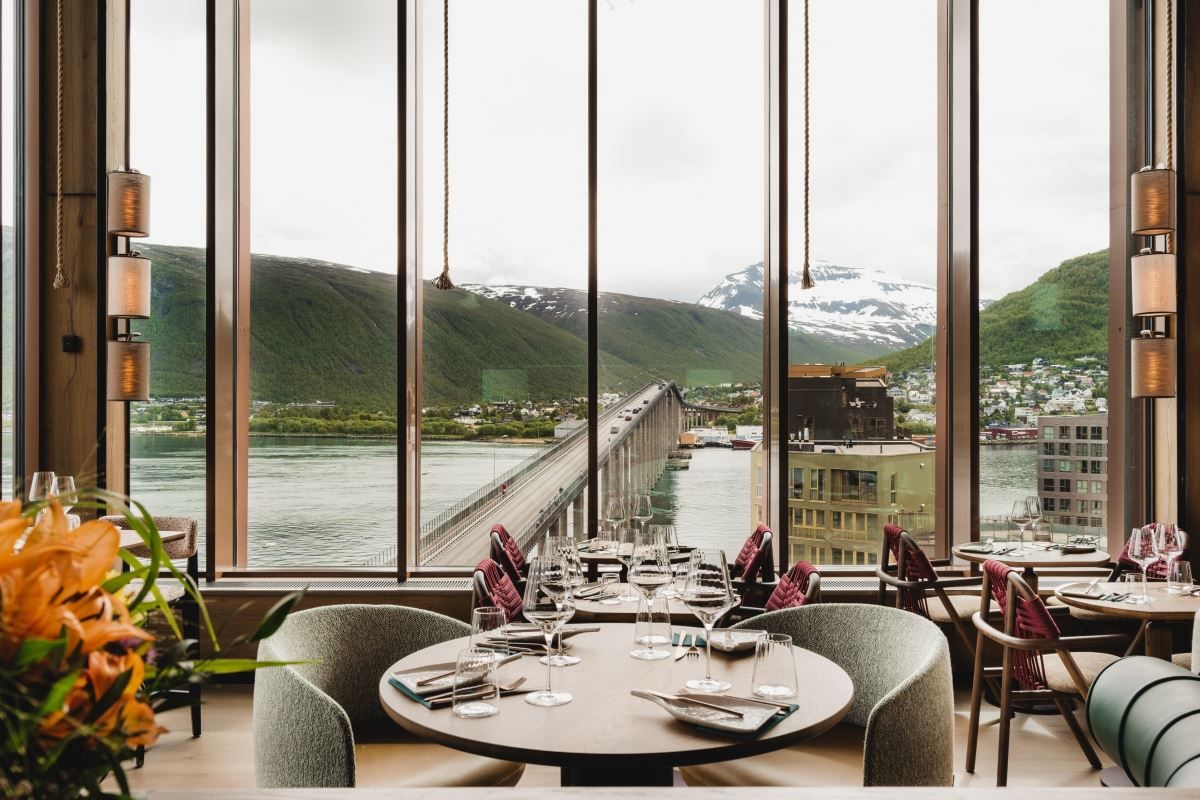 Restaurant med utsikt mot bro, vann og fjell gjennom store vinduer
