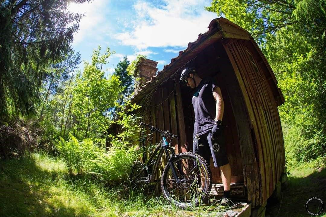 cyclist with bicycle in front of a small cabin