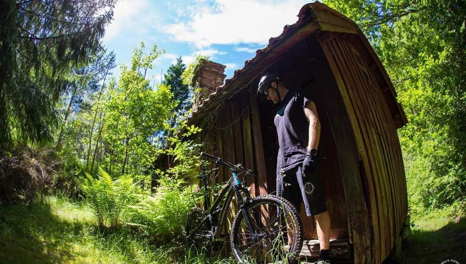 cyclist with bicycle in front of a small cabin