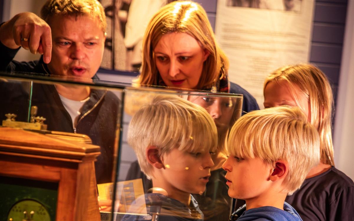 Visitors viewing a historical exhibit through a glass display.