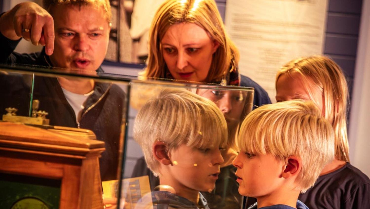 Visitors viewing a historical exhibit through a glass display.