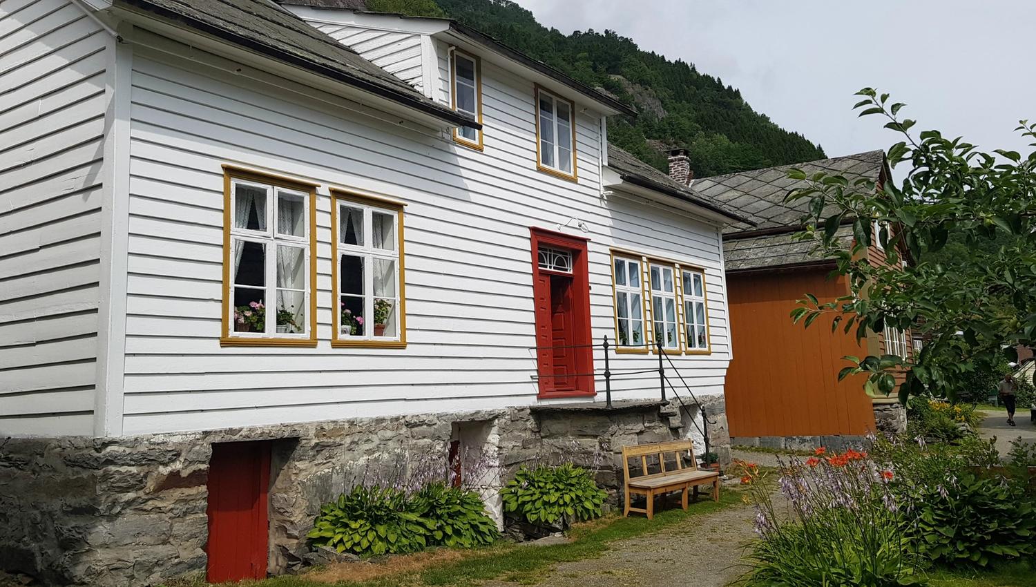 one white and one orange house with a bench outside