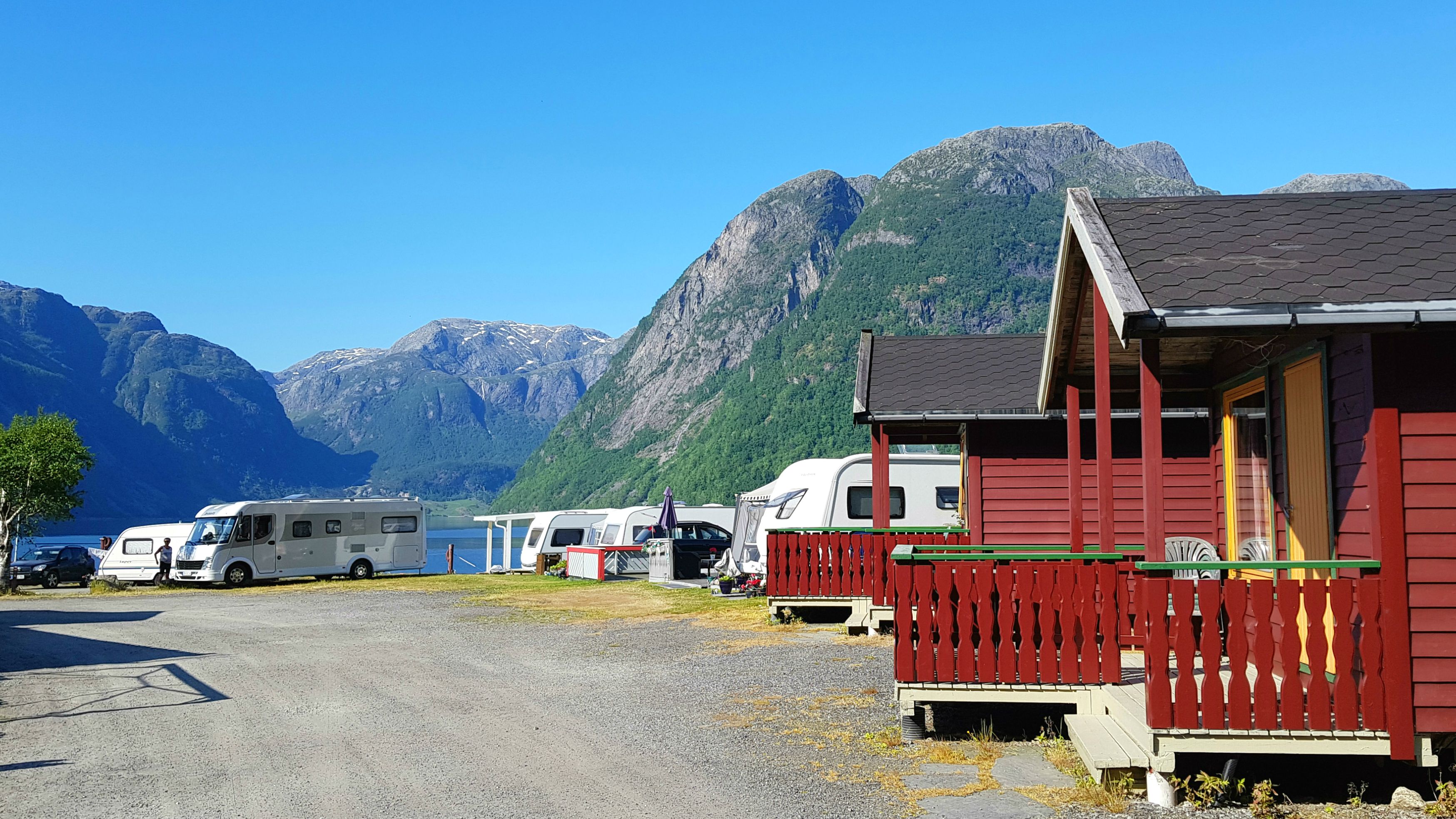 Hytter og campingområde ved vatnet omgitt av natur og fjordlandskap i Hardanger.