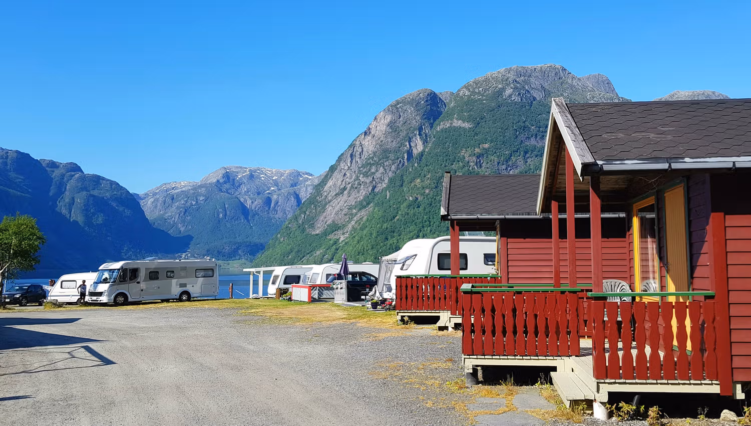 Hytter og campingområde ved vatnet omgitt av natur og fjordlandskap i Hardanger.
