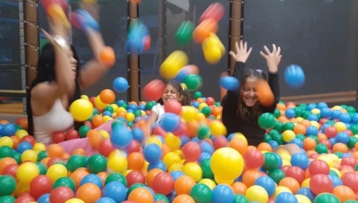 The ballroom, a room crammed full of colorful balls. 3 children are playing and throwing balls into the air.