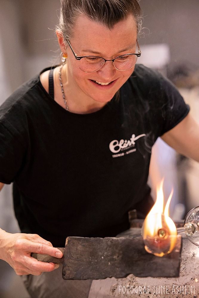 Glassblower shaping hot, glowing glass by hand at Blåst Glass Studio in Tromsø, using traditional glassmaking techniques and tools.