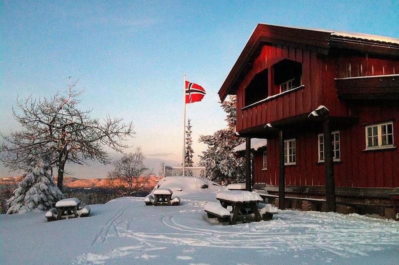 Rød, toetasjes hytte i snøen.