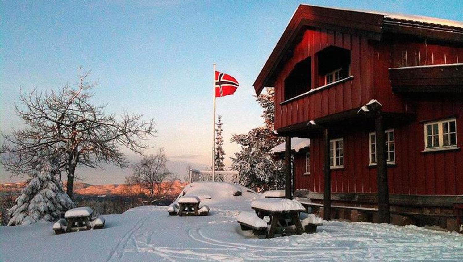 Rød, toetasjes hytte i snøen.