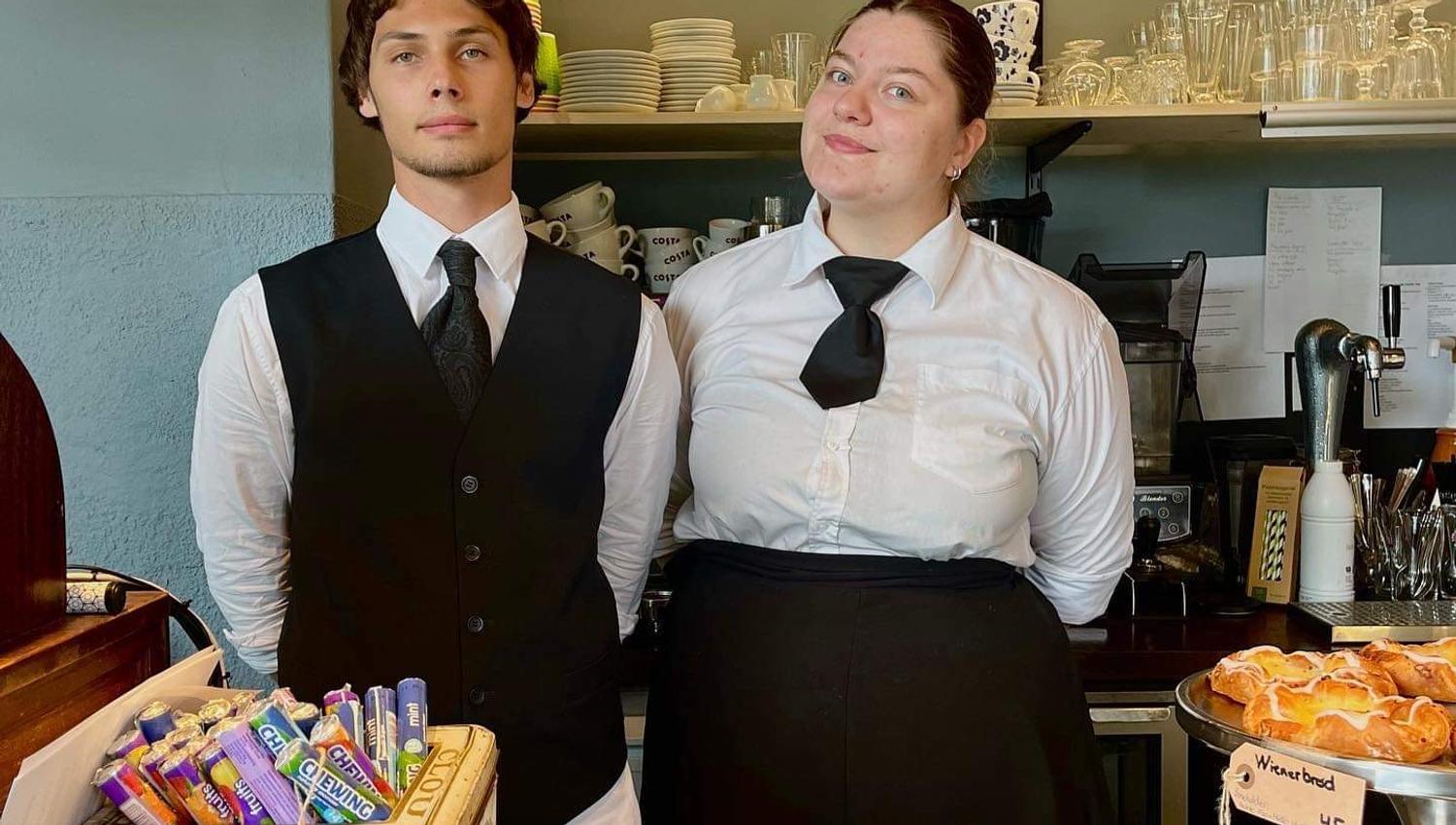 To ansatte ved S.Kagestad som står bak disken i uniform