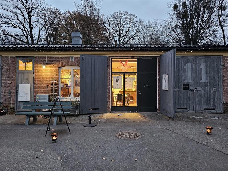 Inngangen til Nummer Ti i en historisk mursteinsbygning på Karljohansvern, med lys fra vinduene.