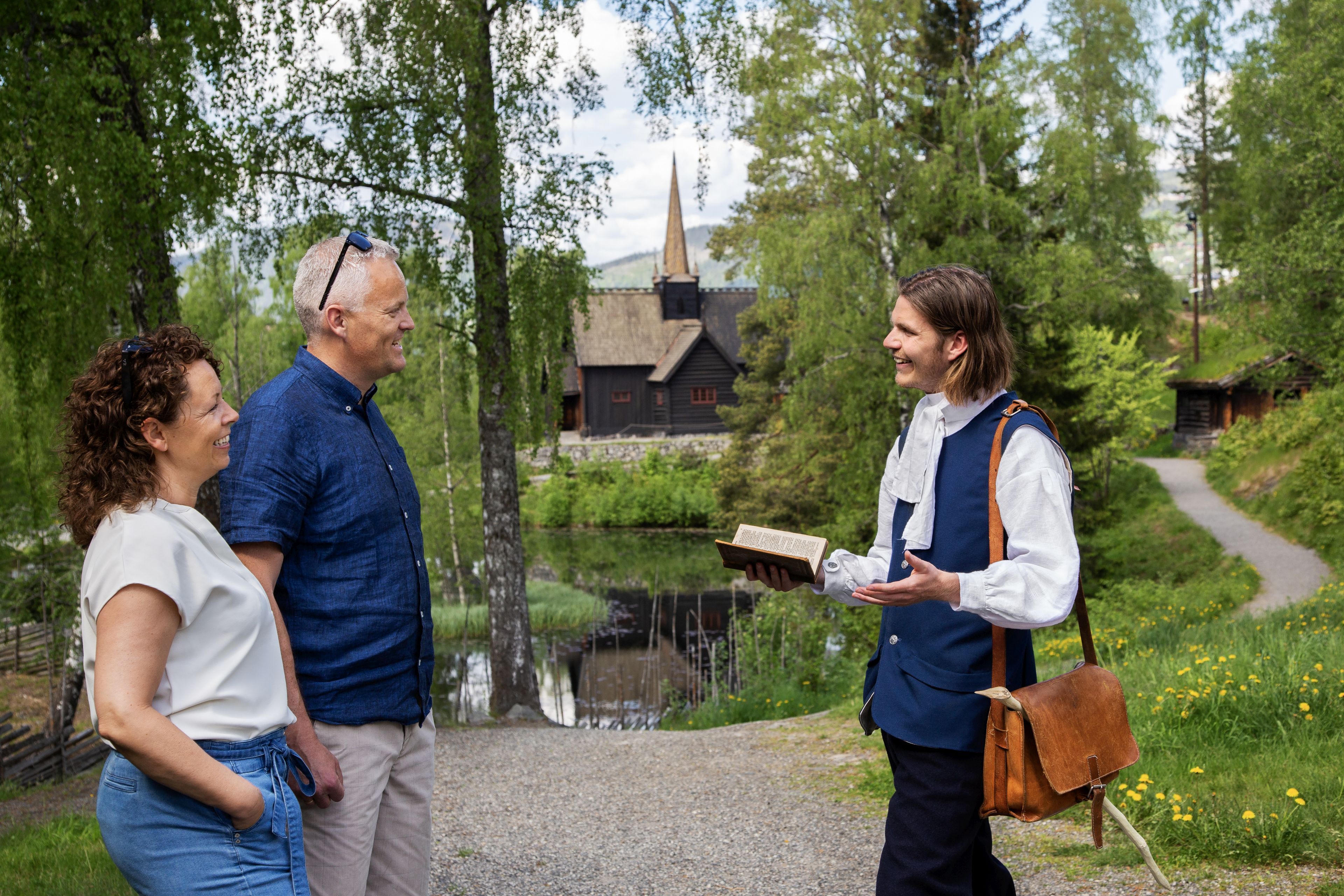 Museumsgjester i møte med en skuespiller foran Garmo stavkirke.