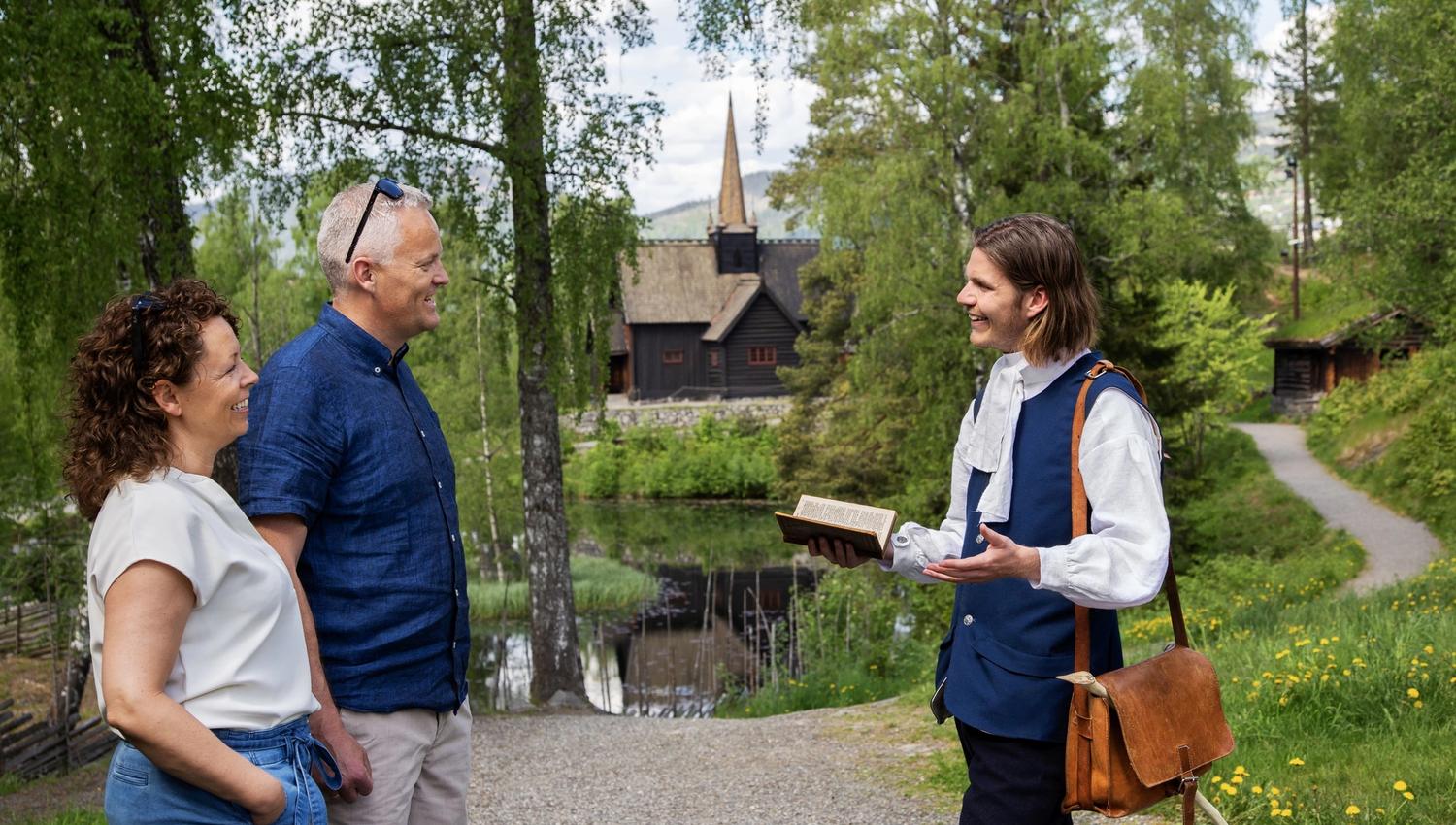 Museumsgjester i møte med en skuespiller foran Garmo stavkirke.
