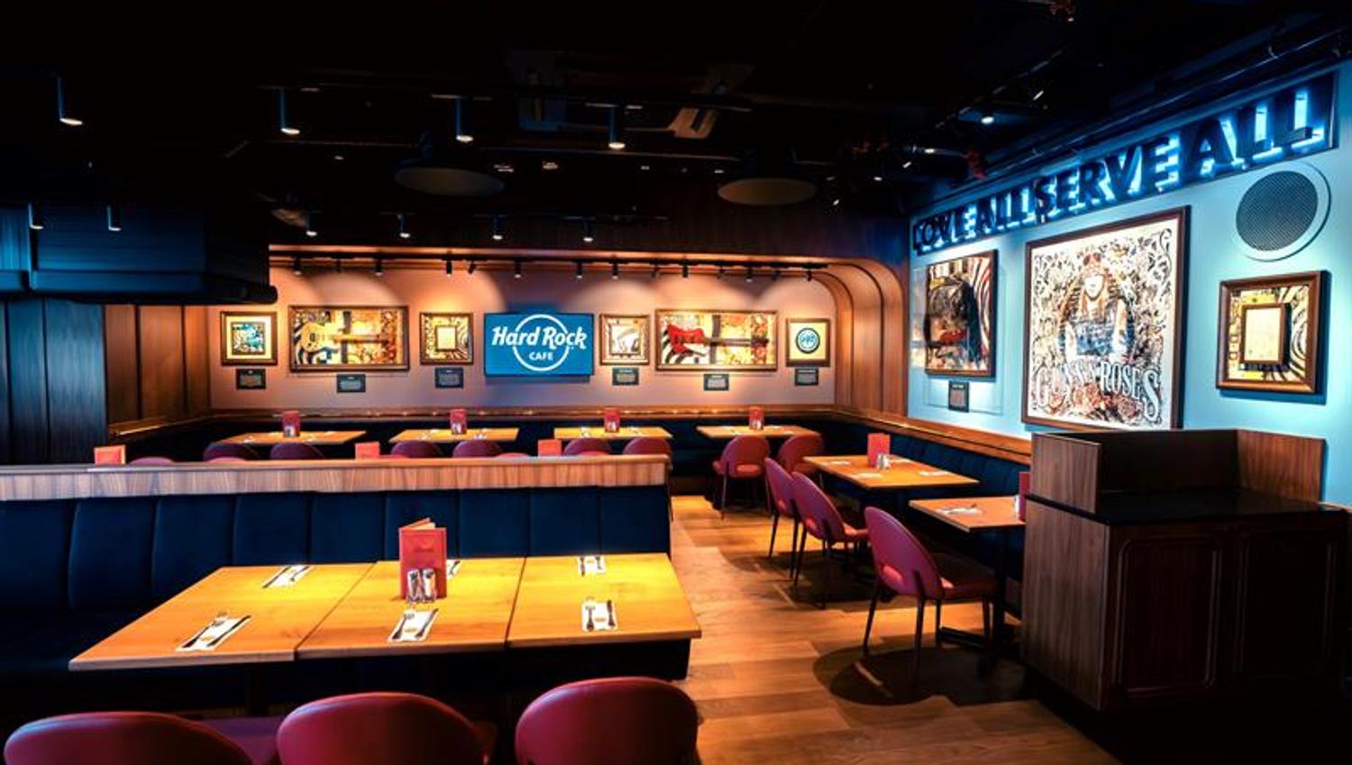 Small square tables with red chairs and various pieces of rock memorabilia on the walls