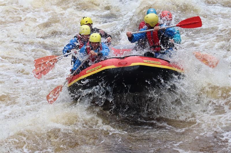Rafter in einer Welle, viel Wasser spritzt auf das Schlauchboot.