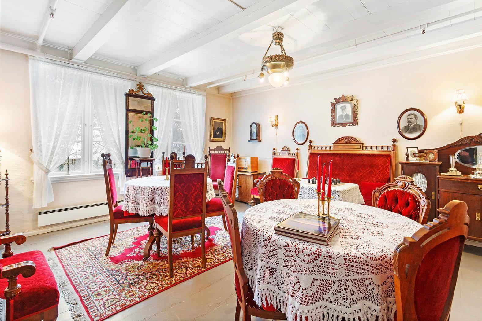 Historic dining room with antique furniture, red velvet chairs, and lace tablecloths at Jaunsen Gjestgjevarstad in Granvin.