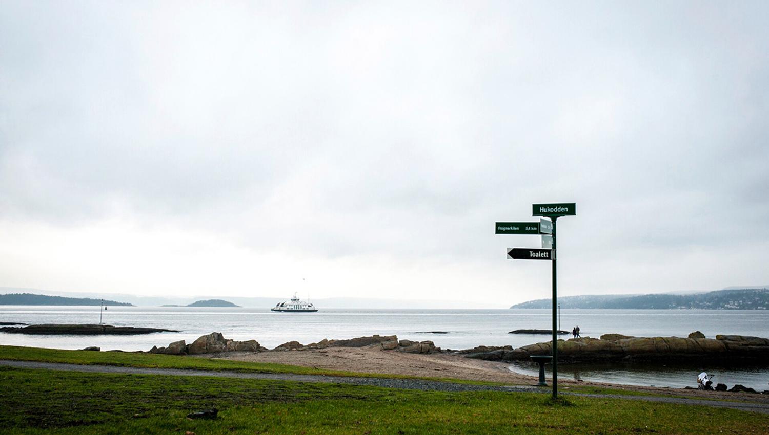 bygdøy beach with a sign and one of the island ferries in the background