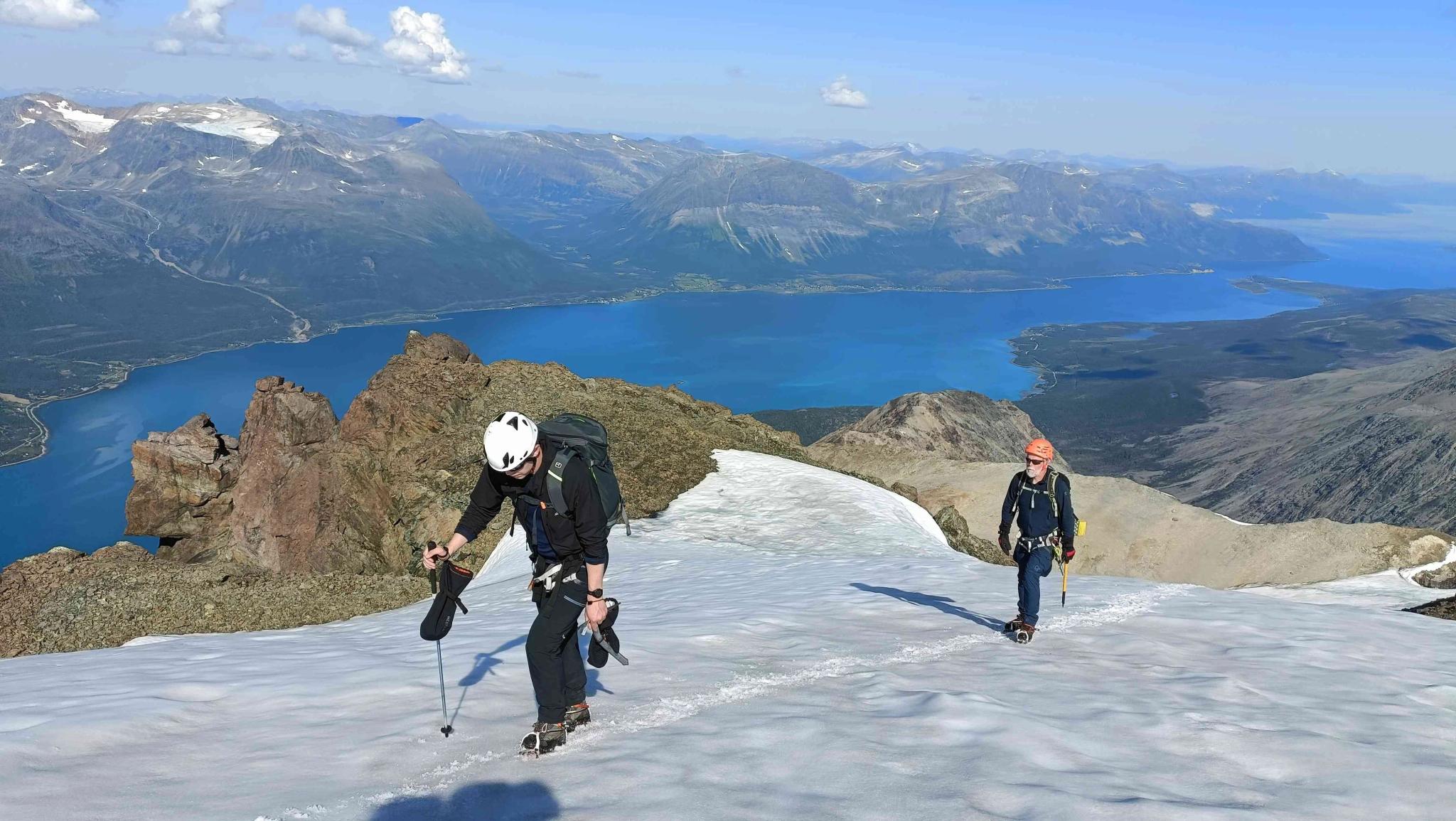 Two persons hiking up a snowcovered mountain.