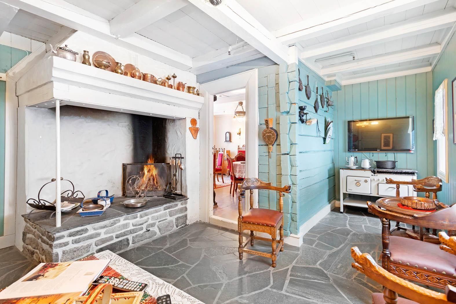 Cozy living room with open fireplace and traditional decor at Jaunsen Guesthouse in Hardanger, Norway.