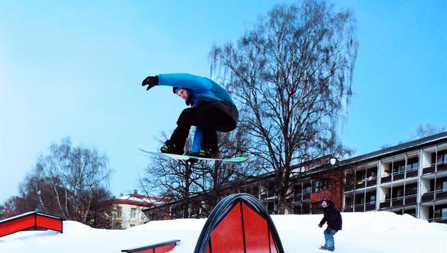 Snøbrettkjører som hopper over en rampe.