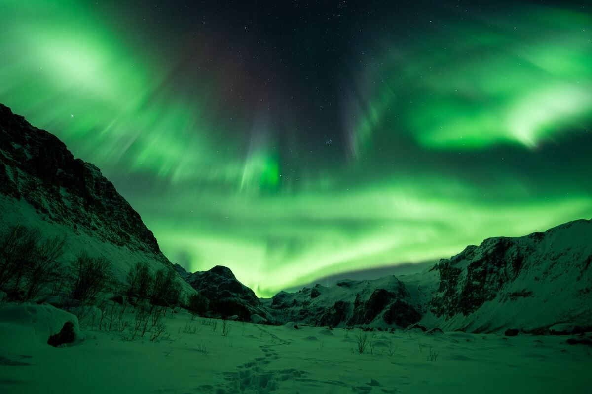The Northern Lights appear from behind a mountain
