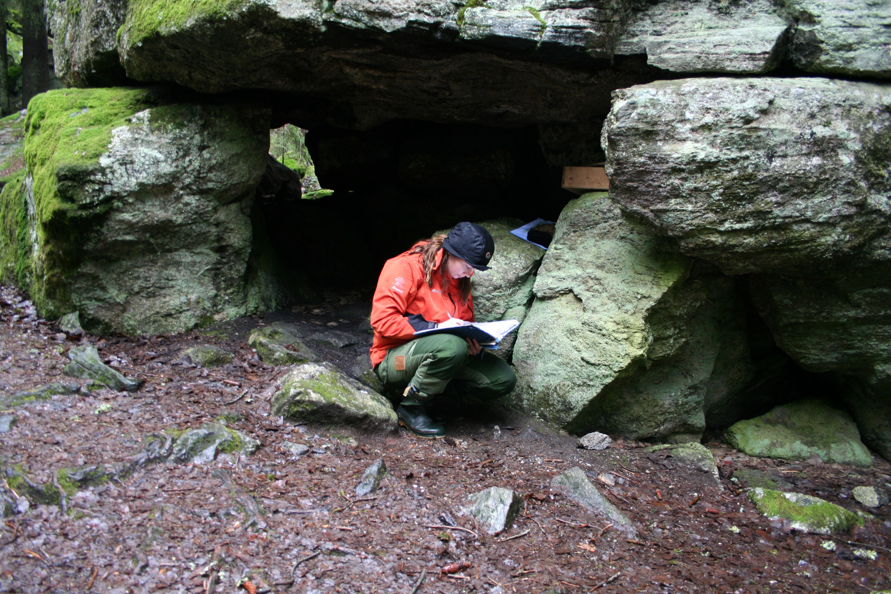 person sitting outside a cave of stones