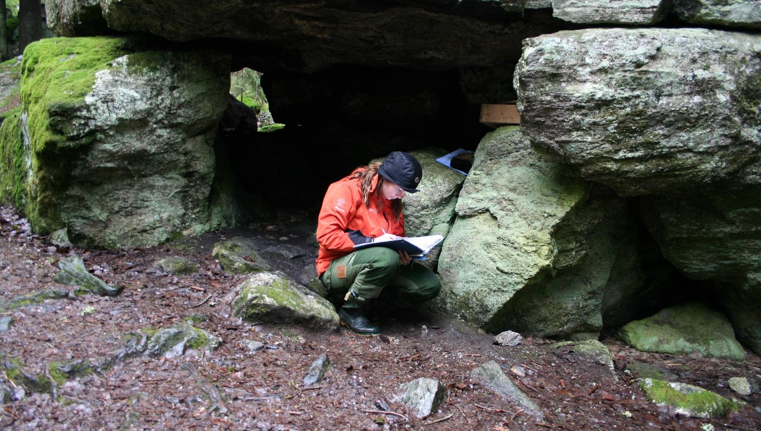 person sitting outside a cave of stones