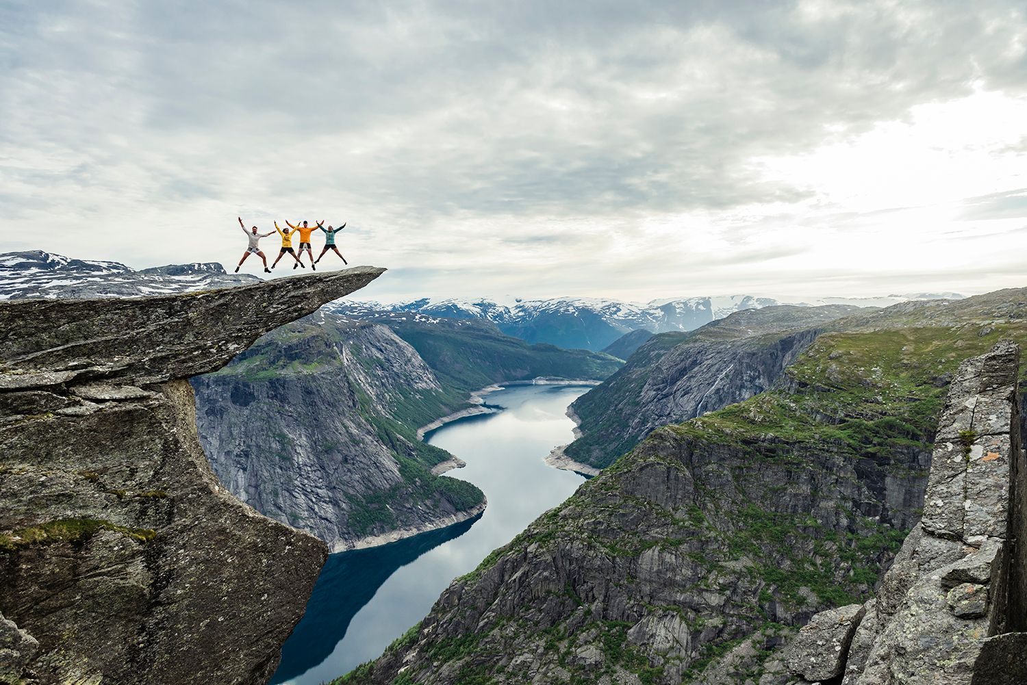 A group of people standing on top of Trolltunga with views towards Ringedalsvatnet lake. 