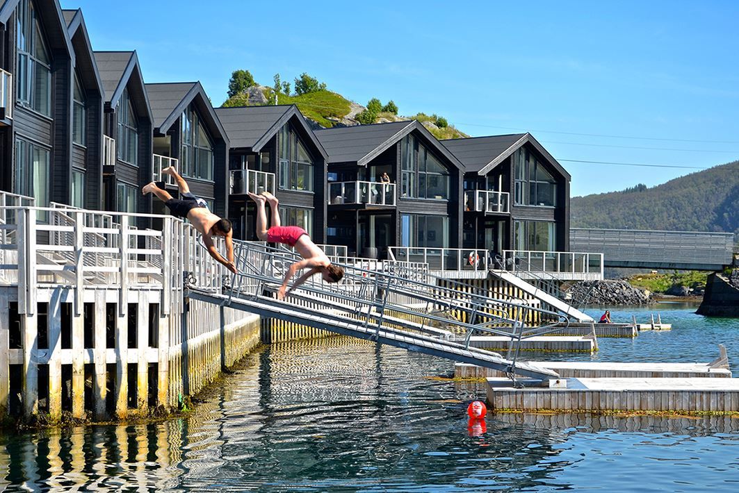 Two people diving from the pier at Hamn in Senja during summer.