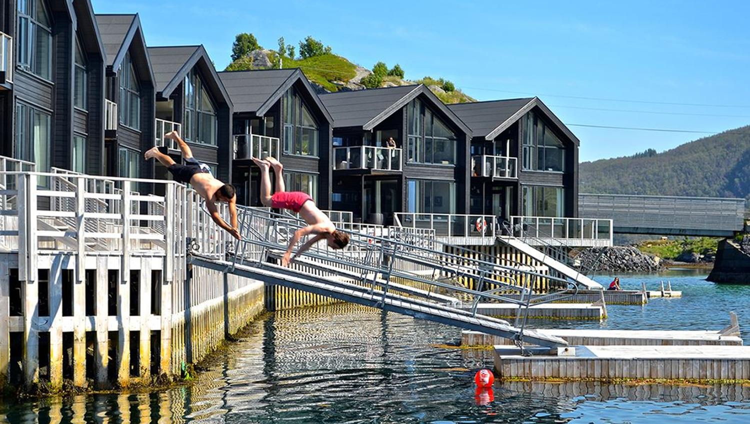 Two people diving from the pier at Hamn in Senja during summer.