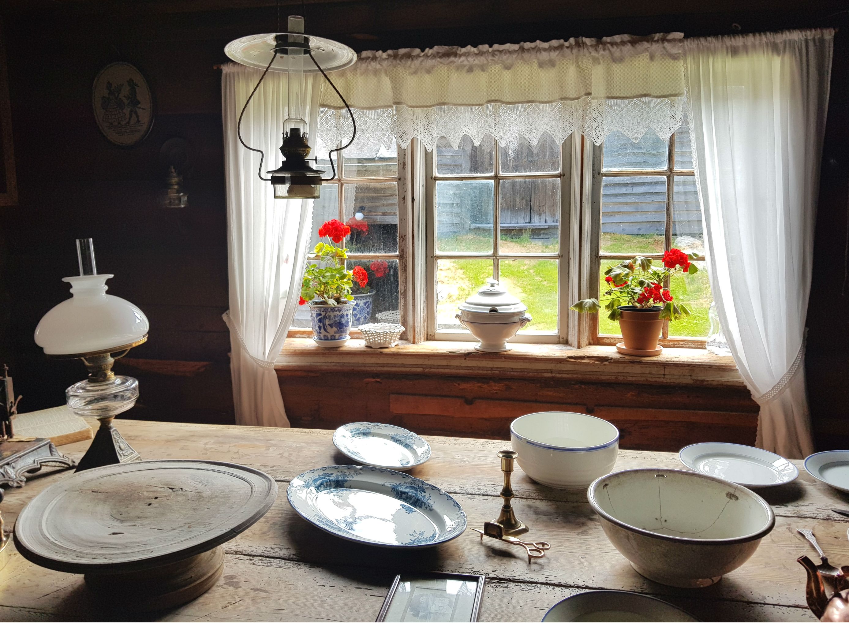 A plated table by a window with flowers and white lace curtains 