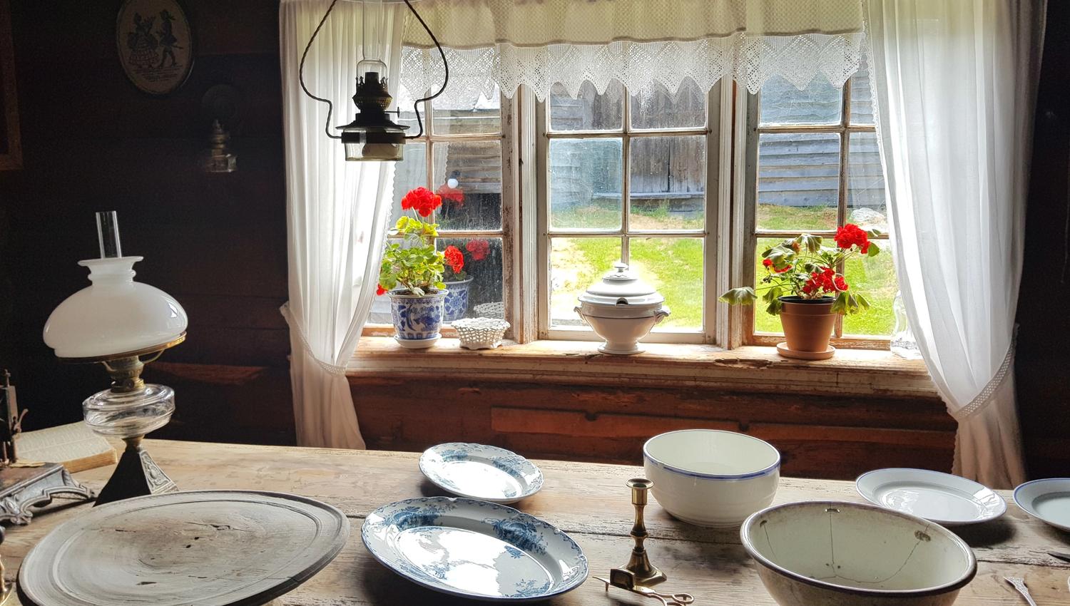 A plated table by a window with flowers and white lace curtains