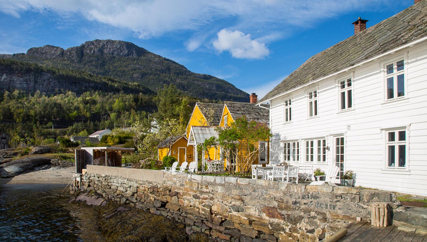 Kramsjø Guesthouse in Hardanger – charming white and yellow waterfront houses surrounded by fjord scenery and majestic mountains.