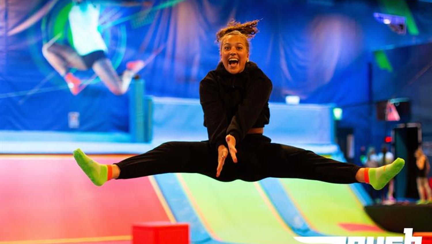 Girl taking a split jump on a trampoline.