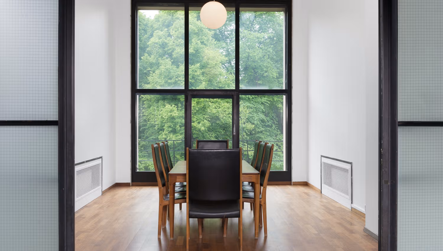 A long table in front of a window with a view towards the park.