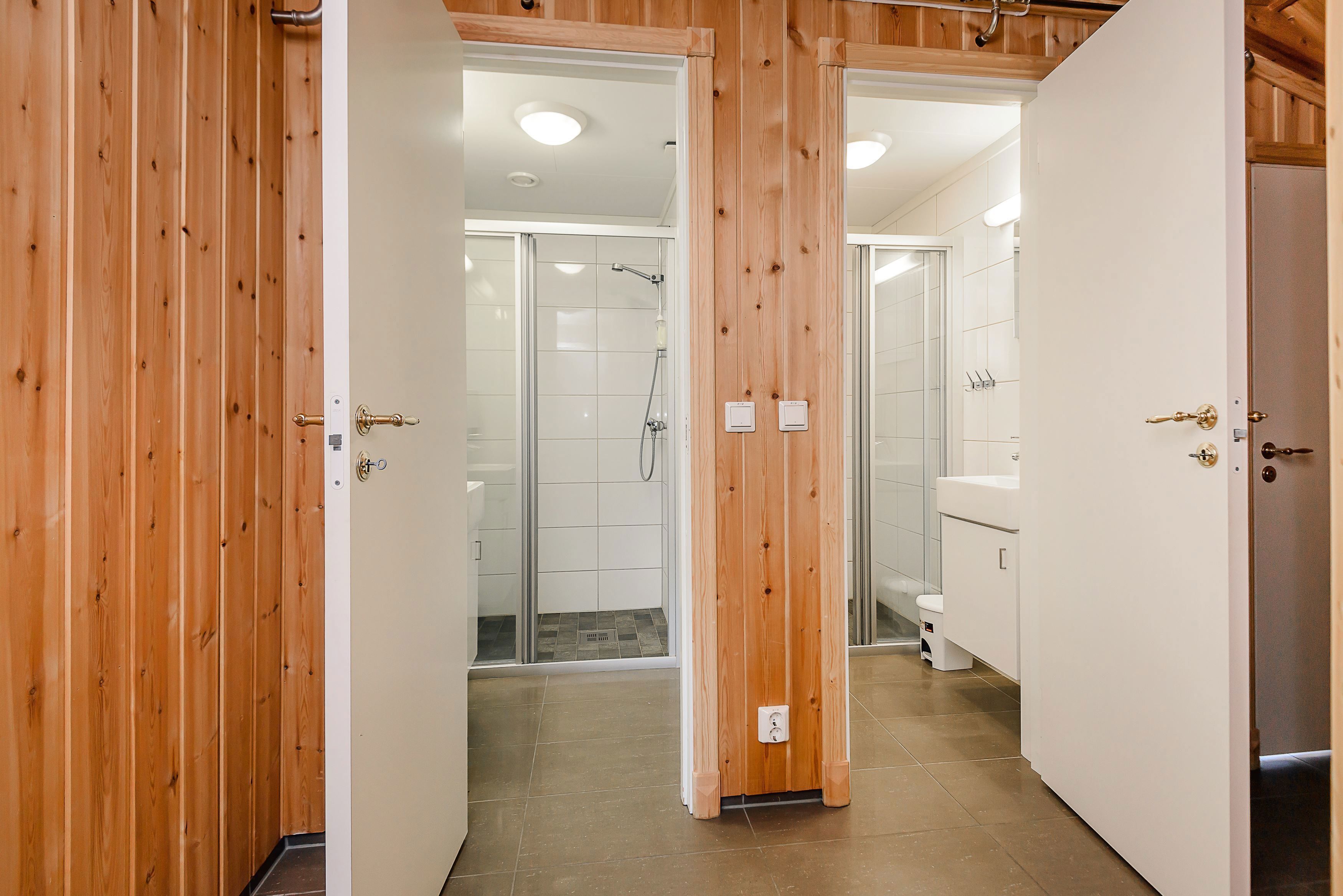 A bathroom with wood paneled wall and shower.