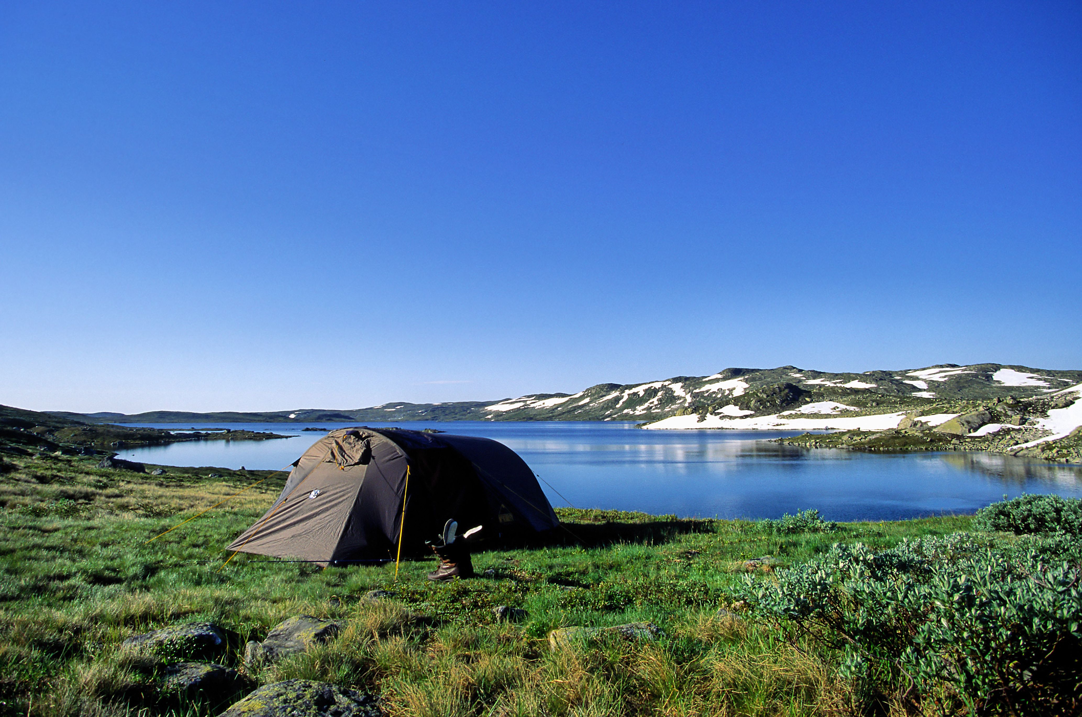 A tent by a mountain lake on a summer day.