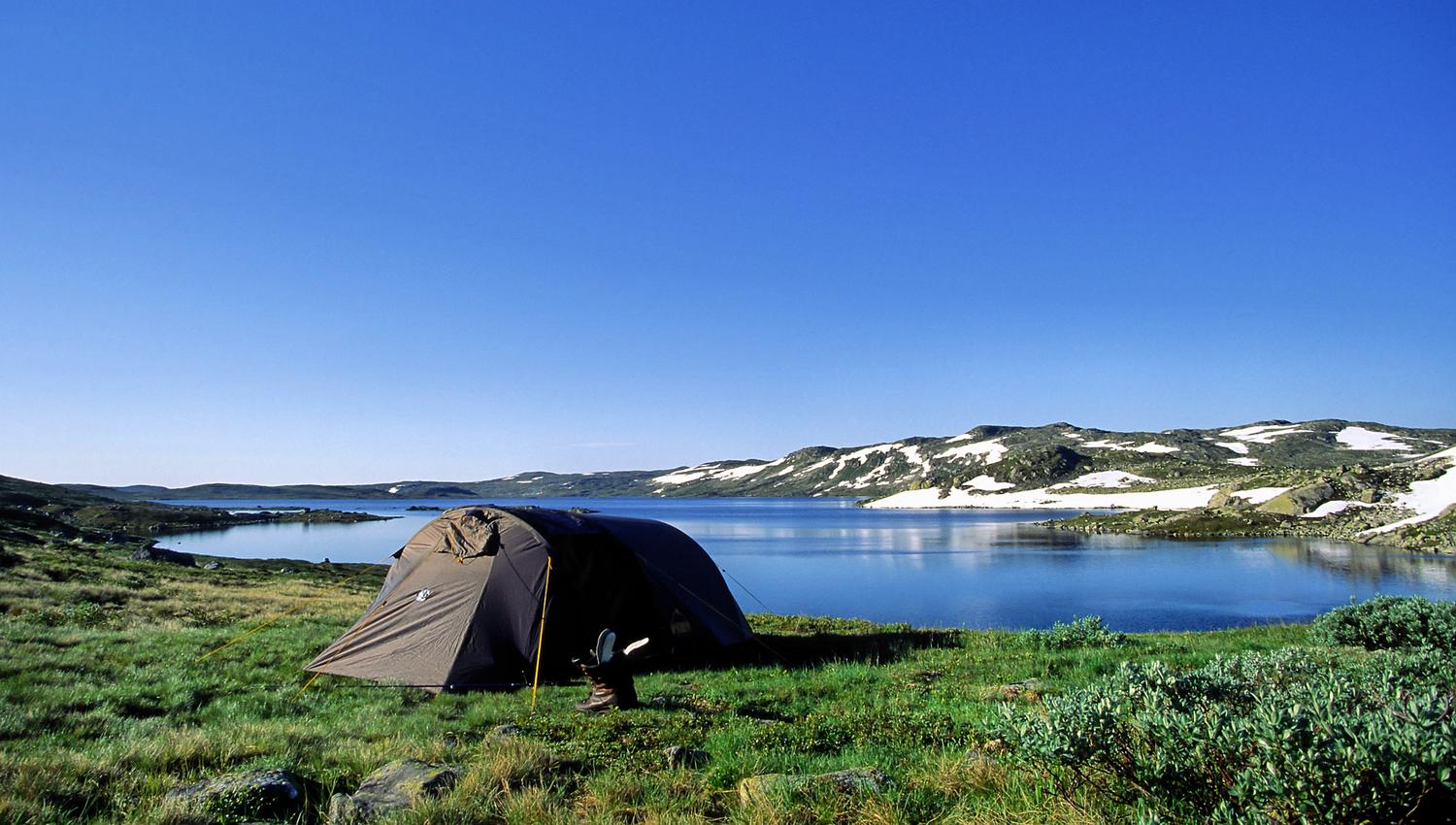 A tent by a mountain lake on a summer day.