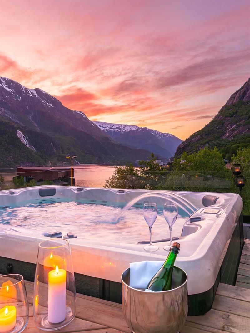 Boblebad på Tyssedal Hotel med utsikt mot fjorden i solnedgang.