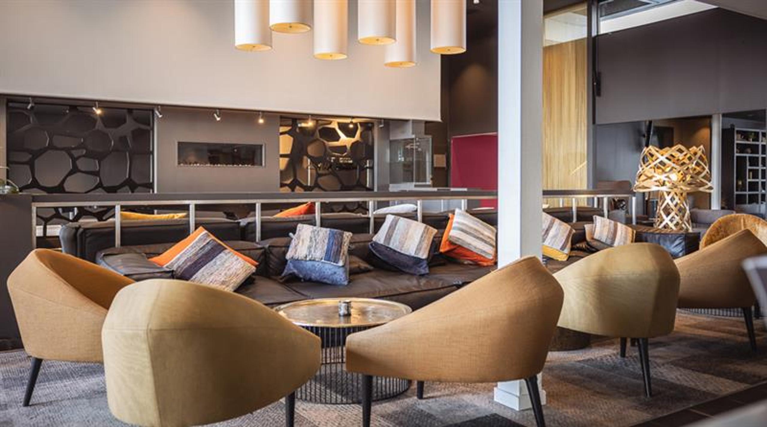 Hotellinngang med moderne arkitektur, parkeringsområde og tydelig skilting