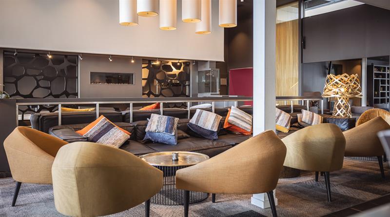 Hotellinngang med moderne arkitektur, parkeringsområde og tydelig skilting