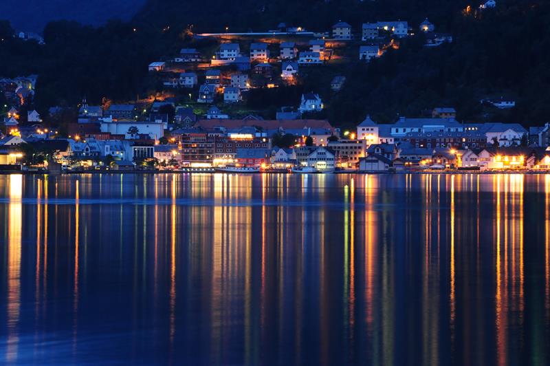Evening lights over Odda and Hardanger Hotel reflecting in the calm fjord water.