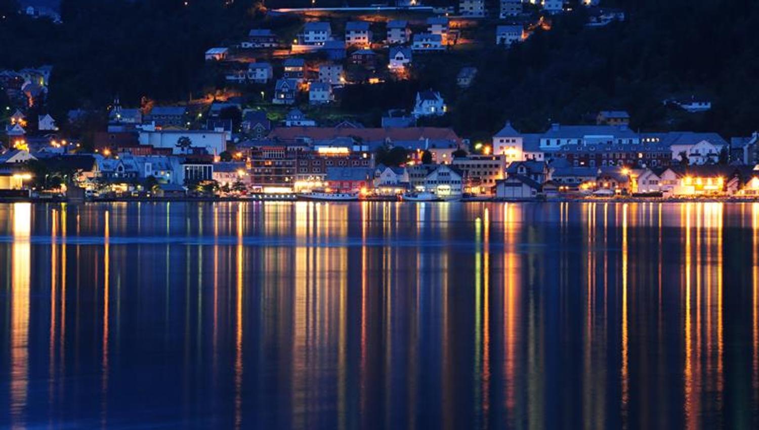 Evening lights over Odda and Hardanger Hotel reflecting in the calm fjord water.