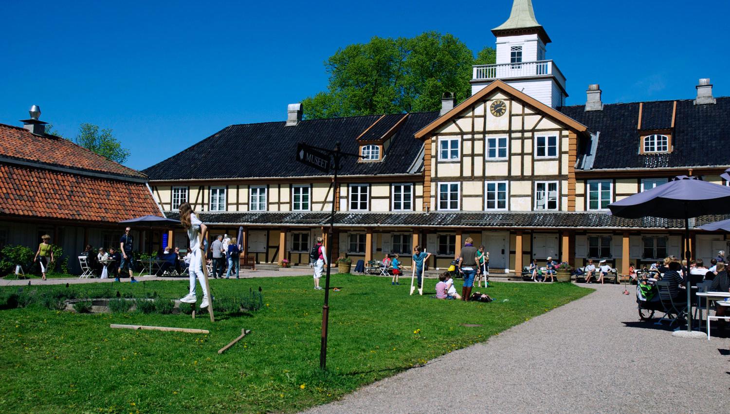 Eksteriør med gressplen, med med mennesker som gjør utendørsaktiviteter.