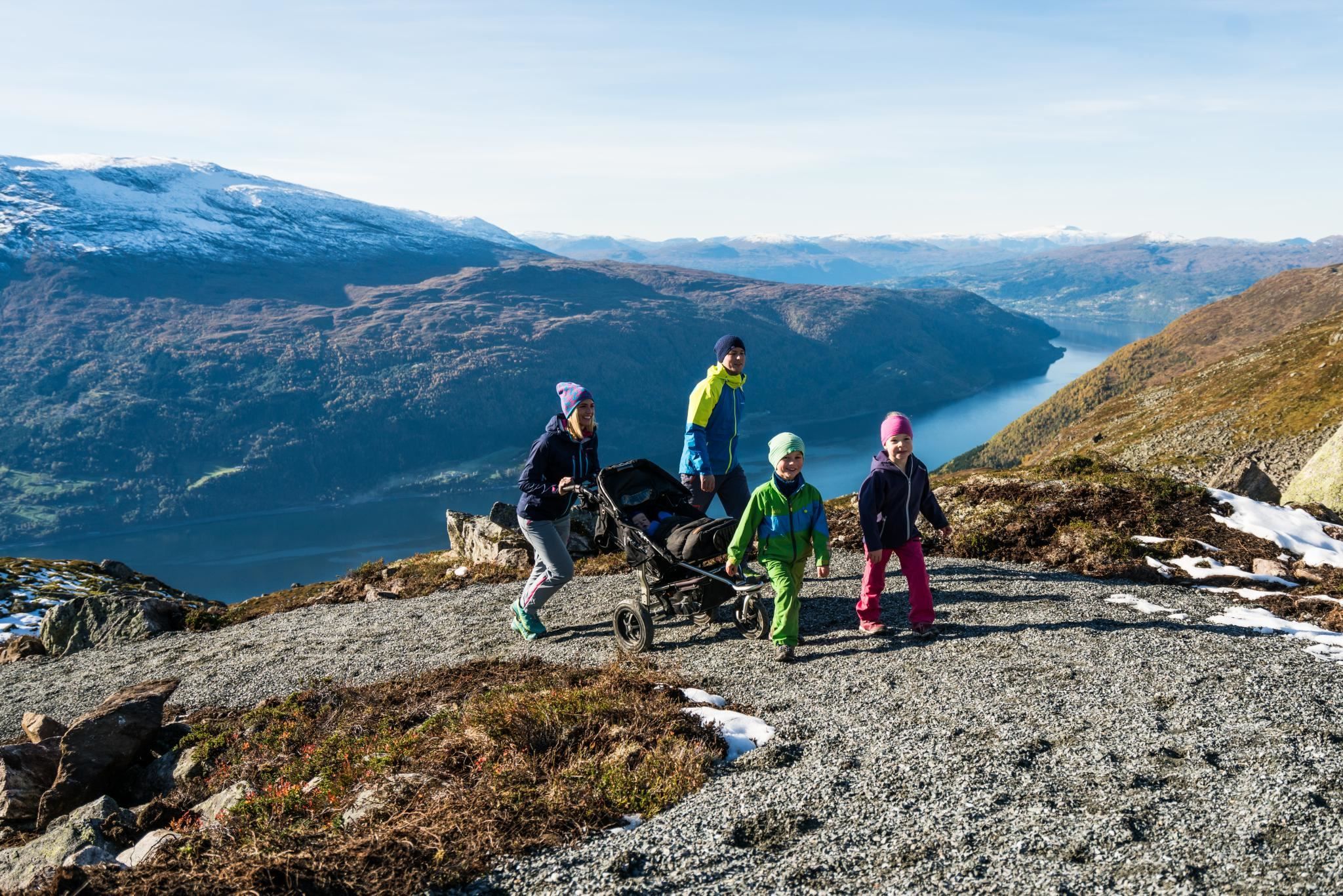 Hikers taking a break on the mountain at Hoven, with wide views of the surrounding fjord and mountains.