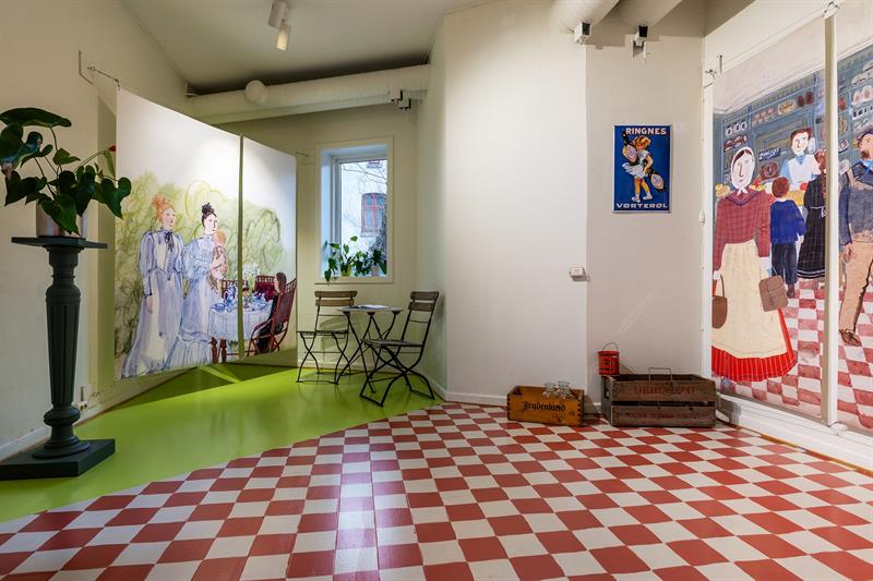 Exhibition room with illustrations, chequered flooring and historic advertising signs in a bright setting.