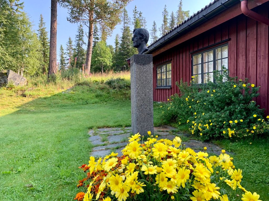 Byste og blomar ved inngangen til Skinnarlandsamlinga i Rauland.
