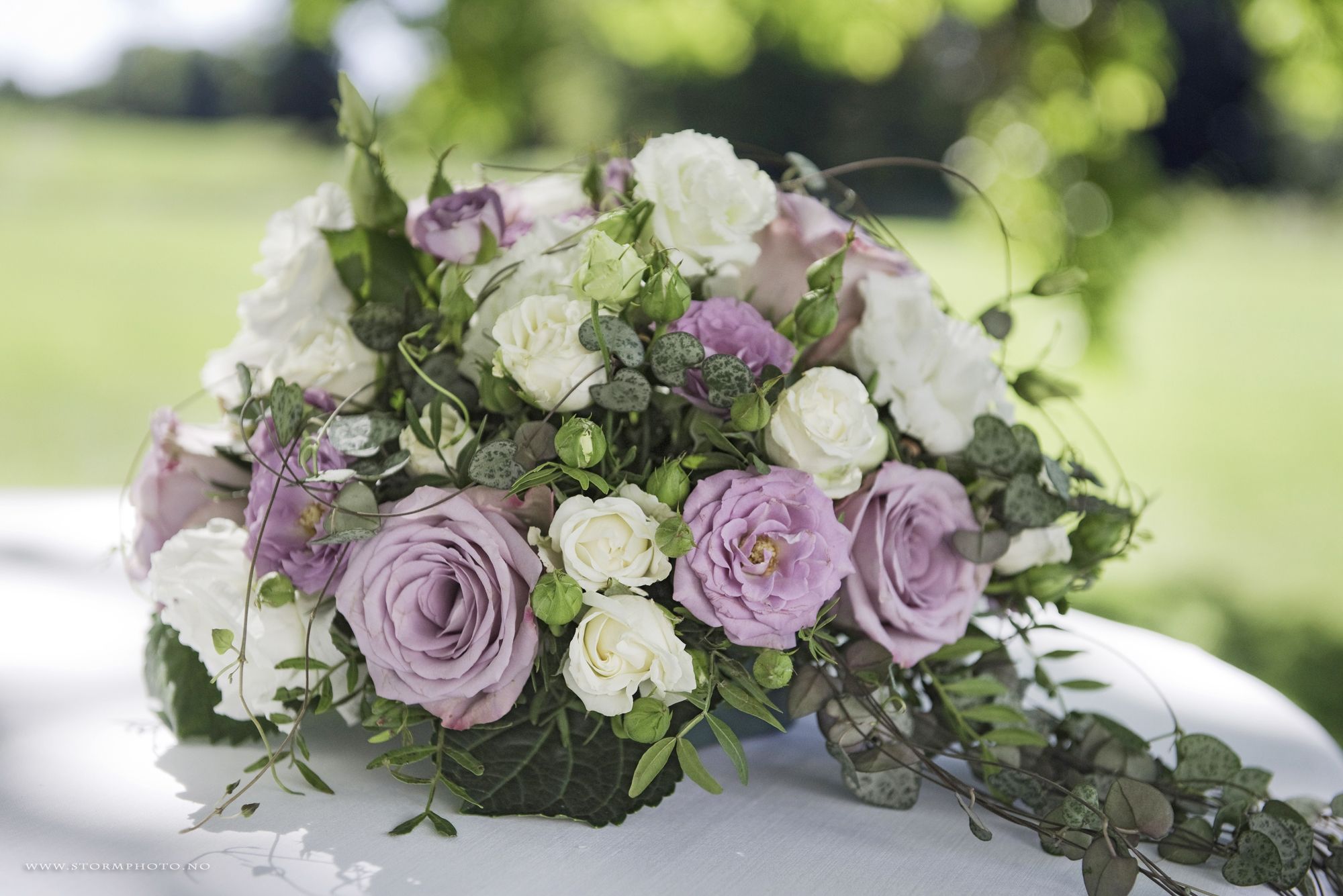 An arrangement of white and purple flowers on a white table cloth